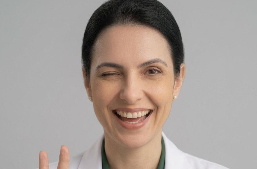 Farmacêutica sorridente fazendo sinal de ok, segurando cartelas de comprimidos